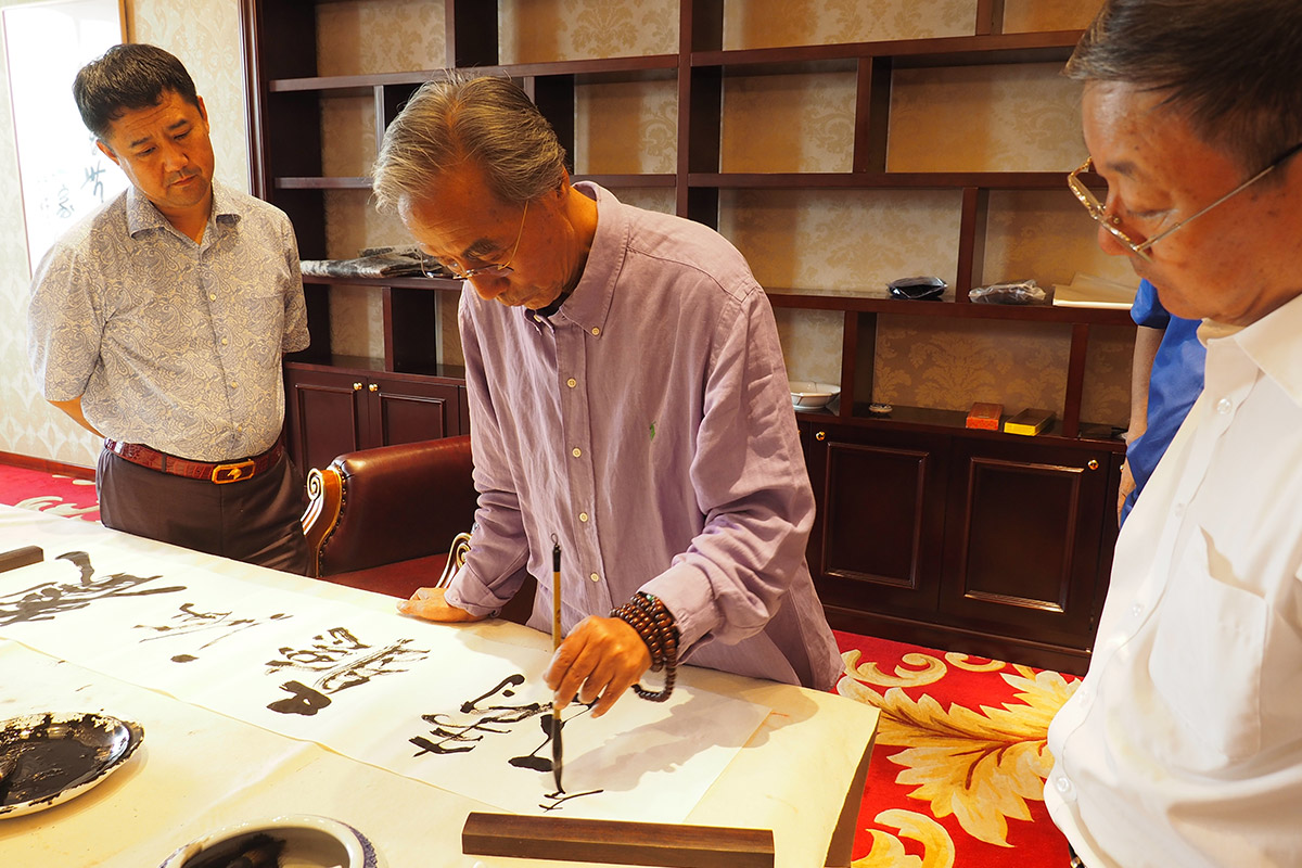 左1昌宇集团董事长李刚-左2著名画家宋雨桂-左3喻国伟（辽宁省文联副主席）-宋雨桂老师正在为董事长李刚题字