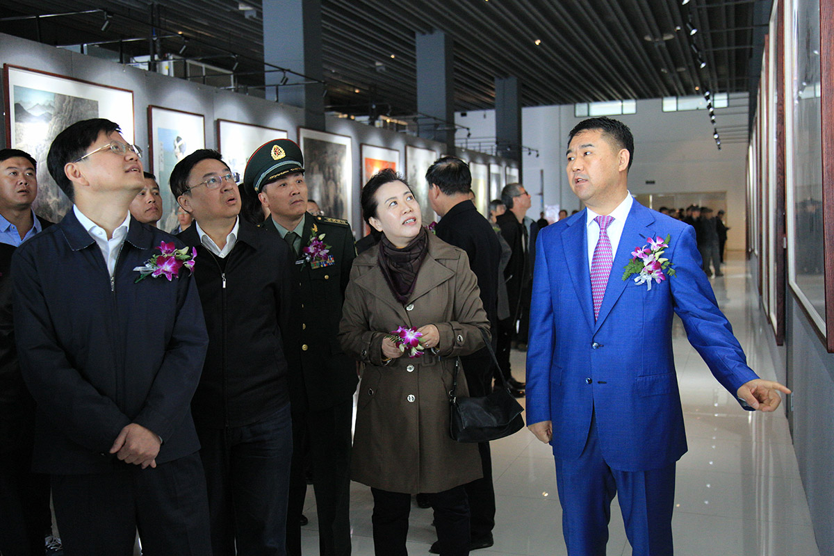 昌宇集团董事长李刚为参加画展省、市领导介绍画展情况